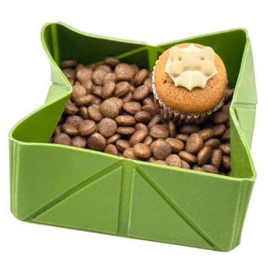 Cocopup London foldable silicone travel dog bowl – khaki, open and filled with dry kibble plus a bone-topped cupcake treat