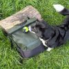 Black Cocopup London ball holder with an Ancol tennis ball attached to a green bag lying on grass